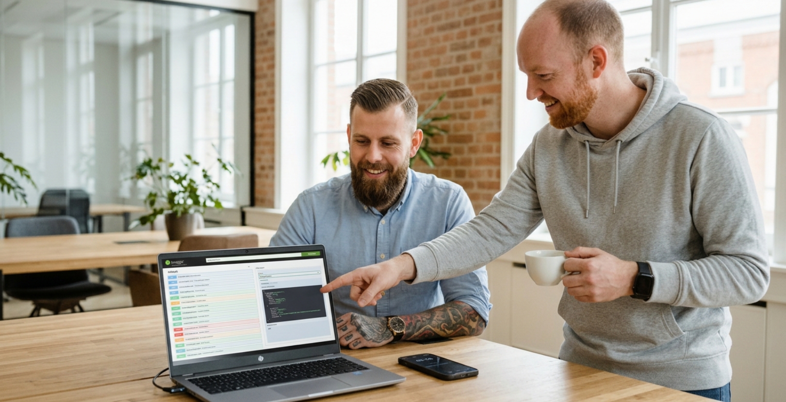 Twee collega's vergelijken website opties op laptop bij bespreking over kosten website laten maken