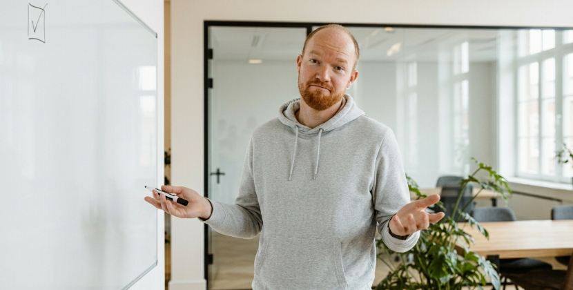 Developer staat bij bijna leeg whiteboard met klaar-gebaar, project te snel afgerond