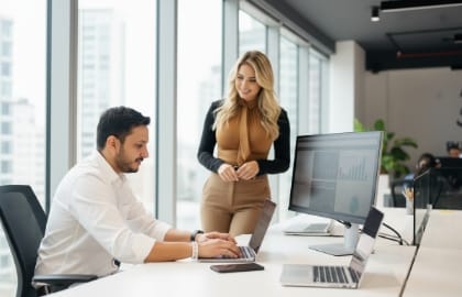 Two teammates reviewing a managed web-hosting dashboard in a bright office