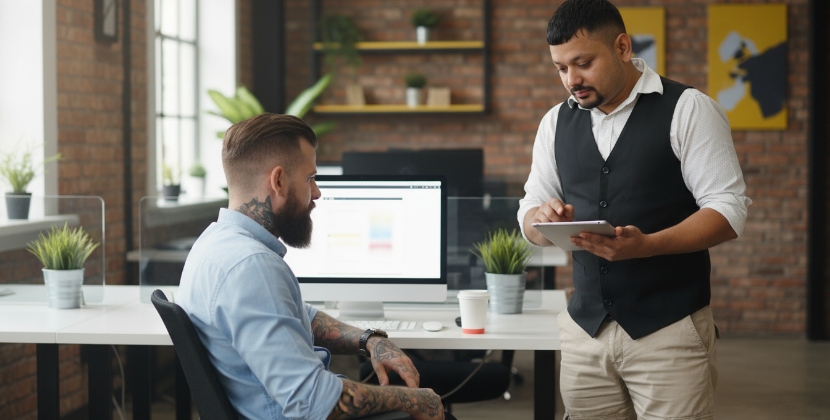 Twee mannen bespreken webshop strategie op tablet en desktop in modern kantoor