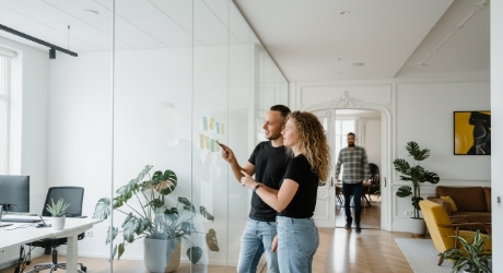 man en vrouw bespreken SaaS onboarding flow op glazen wand met sticky notes