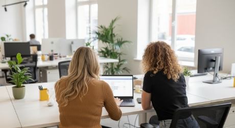 Twee collega's bespreken app design strategie voor gebruikersretentie op laptop