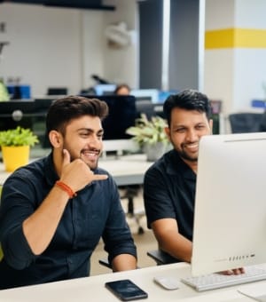 Two coworkers reviewing work together on a desktop monitor