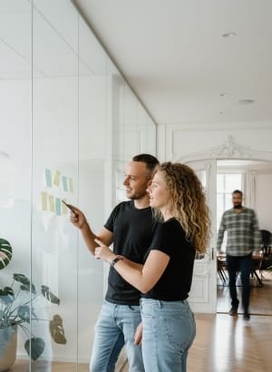 Colleagues planning on a glass wall with sticky notes