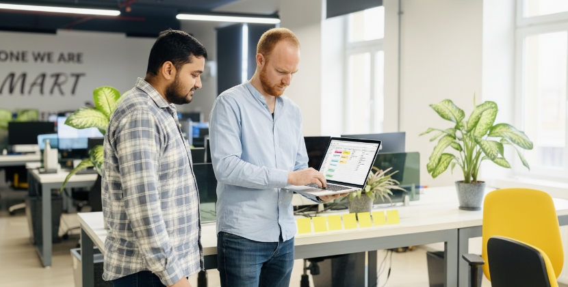 Twee collega's reviewen website contentstructuur en templateplan op laptop staand in kantoor