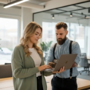 Twee collega’s bekijken samen een laptop in een modern kantoor