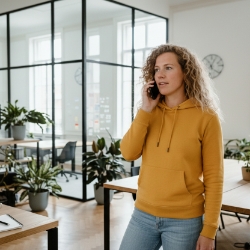 Collega voert een telefoongesprek in een kantoor met planten en glazen ruimtes op de achtergrond.