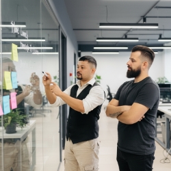 Studio Ubique team plant sprint op glaswand met sticky notes in modern kantoor