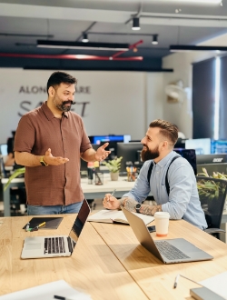 Collega’s bespreken webdesign tarieven aan bureau met laptops, Studio Ubique webdesign bureau sfeer