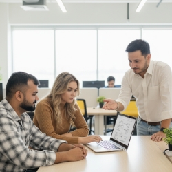 Teamreview rond laptop, focus op scope en aanpak, Studio Ubique kantoor met daglicht