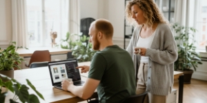Developer werkt op laptop aan SEO en laadsnelheid in een lichte werkruimte met planten in een webdesign bureau