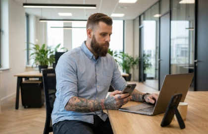 Ontwikkelaar inspecteert mobiele app op fysiek toestel naast laptop in Zwols kantoor
