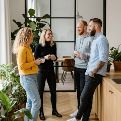 Vier collega's genieten samen van een pauze bij de koffiehoek van een custom website development studio in Zwolle