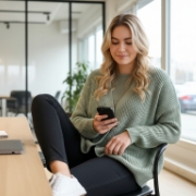 Vrouw bekijkt een Android app op haar smartphone, gezeten in een modern kantoor