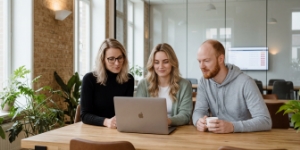 Teambespreking tijdens het traject voor een zakelijke website laten maken, drie collega's kijken naar laptop