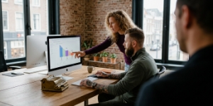Twee collega's bekijken Google Analytics funnel-analyse op iMac
