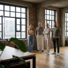 Team Studio Ubique in industrieel kantoor Rotterdam met bakstenen wand en skyline door raam, webdesign Rotterdam