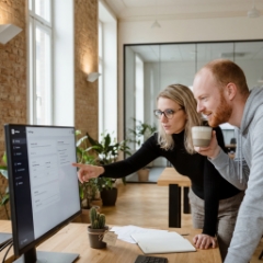 Collega's bespreken webdesign Utrecht strategie bij beeldscherm in kantoor