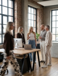 Four Studio Ubique colleagues in conversation in the Zwolle industrial office, fifth colleague walking past with motion blur