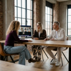 Three Studio Ubique colleagues in a hybrid meeting with the remote team via a screen in the Zwolle industrial office