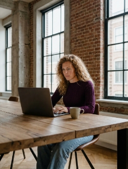 Colleague working focused on a MacBook at a wooden table in the Zwolle industrial office