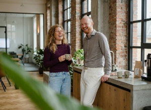 Twee collega's lachen tijdens een koffiemoment in de keuken van het Zwolse industriële kantoor