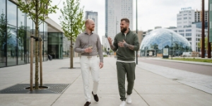 Twee collega's van SEO bureau lopen door modern Eindhoven, hoogbouw en Blob op achtergrond