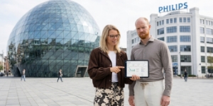 Twee SEO-specialisten bespreken zoekstrategie op tablet voor de Blob in Eindhoven, Lichttoren op achtergrond