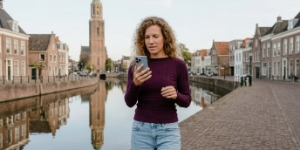 Collega raadpleegt AI-zoekmachine op telefoon bij gracht in Zwolle met Peperbus op achtergrond