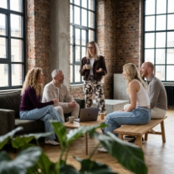 Five Studio Ubique colleagues gathered in the break corner of the Zwolle industrial office, conversation on sofa and bench