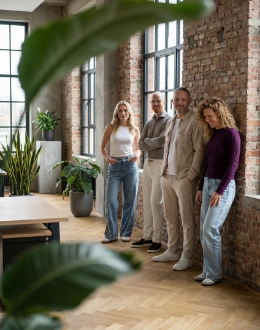 studio-ubique-teamportret-bakstenen-muur-vier-collegas