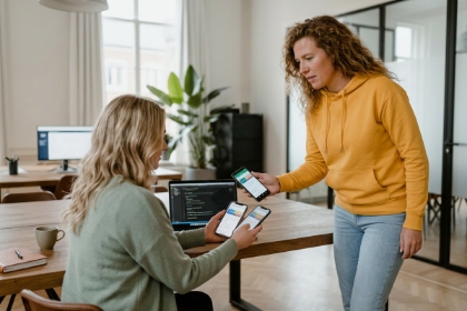 Two team members testing an app on phones at a desk, Android development with Kotlin and Jetpack