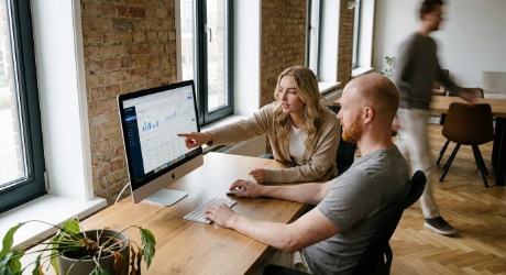 Ontwikkelaar en productmanager aan een houten bureau in een Zwols kantoor die een SaaS website lanceerchecklist bekijken op een groot scherm, zacht daglicht, candid opname