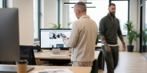 Ontwerper controleert een responsive layout op een iPhone, collega loopt voorbij.