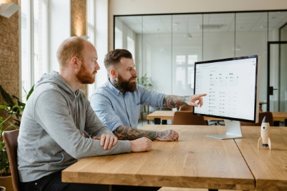 Two Studio Ubique developers working on a headless CMS and GraphQL setup at an iMac