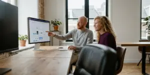 Two designers reviewing a design system component library on screen.