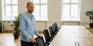 Team member standing beside long meeting table in conference room, representing flexible monthly hours that roll over in website support packages