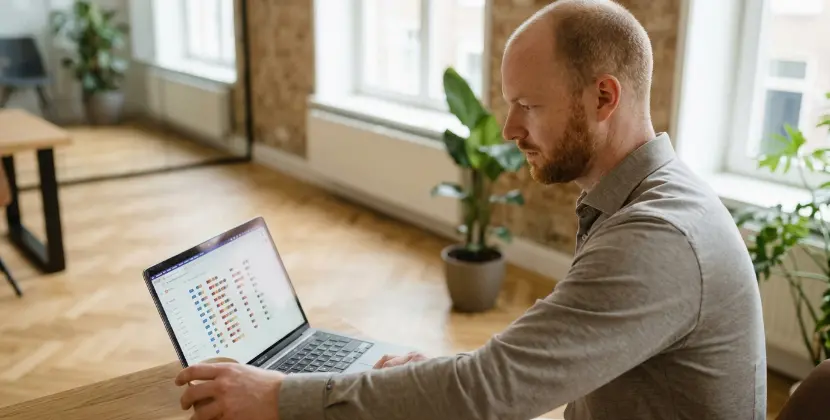 Marketeer checkt rustig een abstracte account tracker op een laptop en pakt een kop koffi