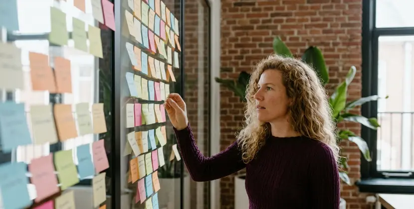 Strateeg bij een sticky-note muur als funnel, verplaatst een briefje