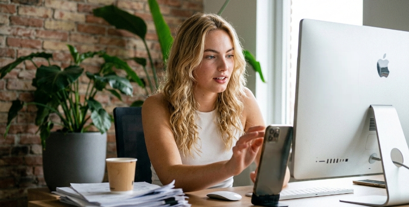 Persoon die een mobiel bestelproces test op een telefoon terwijl een collega het scherm op een desktop bekijkt, over-de-schouder shot, kantoor in Zwolle