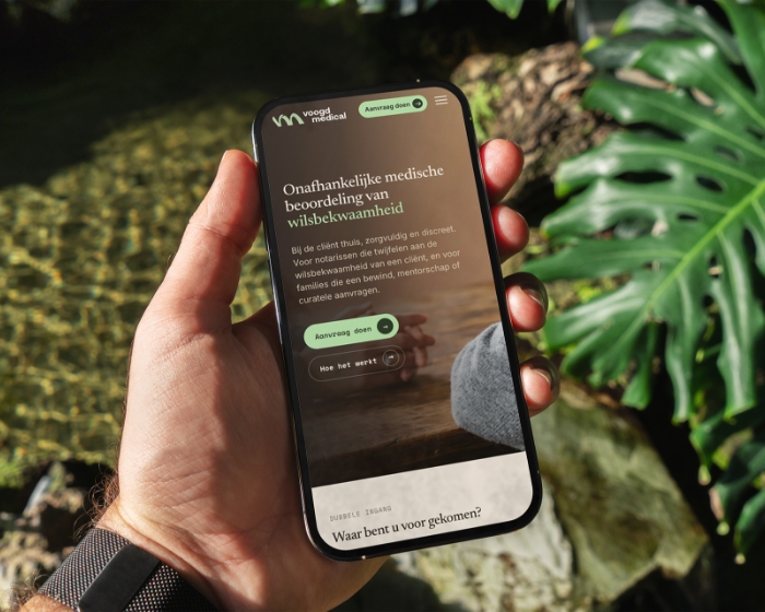 Hand holding a phone with the Voogd Medical home page about assessing wilsbekwaamheid