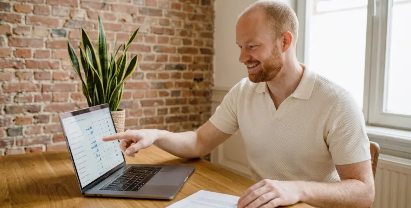 Marketeer wijst naar een rij in een abstracte datatabel op een laptop tijdens campagnereview