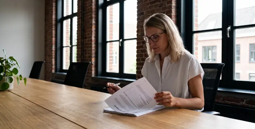 Campagnemanager slaat een pagina om van een geprint maandrapport met de laptop dicht