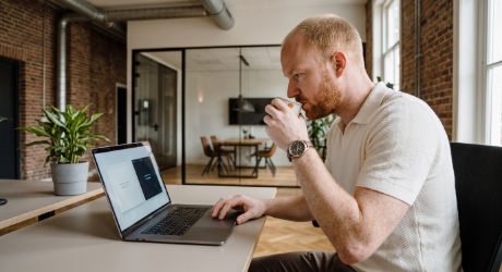 Ontwikkelaar bekijkt serverreactietijden op een laptop terwijl twee hostingpakketten op een tweede scherm worden vergeleken